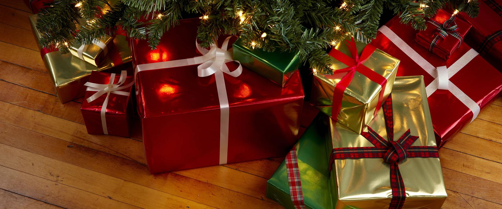 Regali di Natale avvolti in carta colorata sotto l'albero decorato.